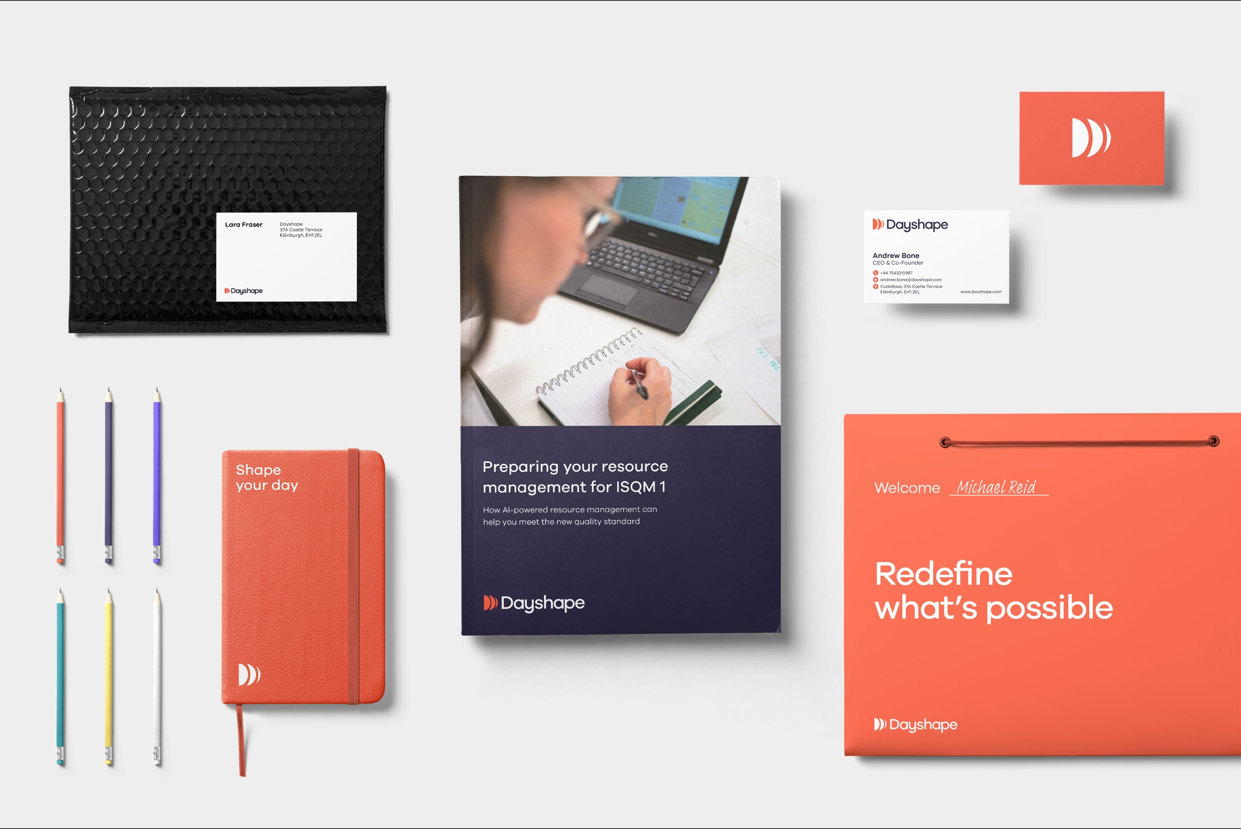 A montage of business cards, promotional items and company onboarding materials with Dayshape identity branding. An orange folder states “”Redefine what’s possible and a pad state “Shape your day”