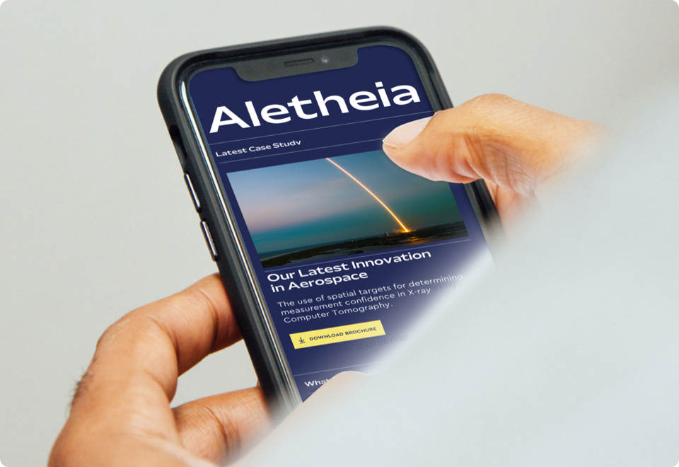 A hand holds a mobile phone looking at the "Alethia" site.